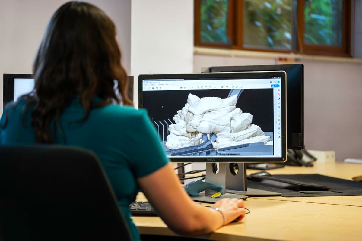 Engineer designing 3D CAD plant models and piping routing on workstation monitors